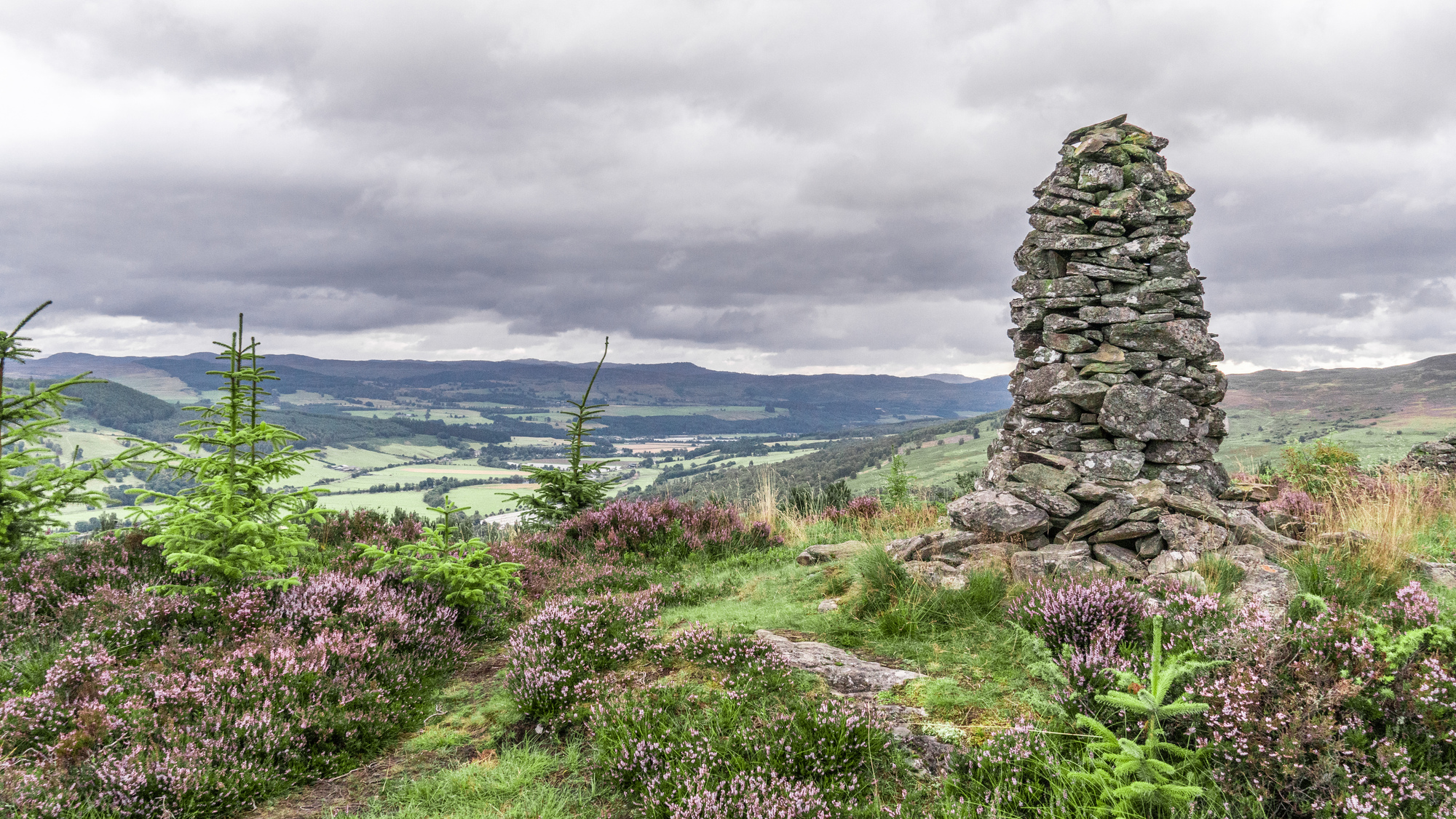 A stone carin on a hillside overlooking a valley