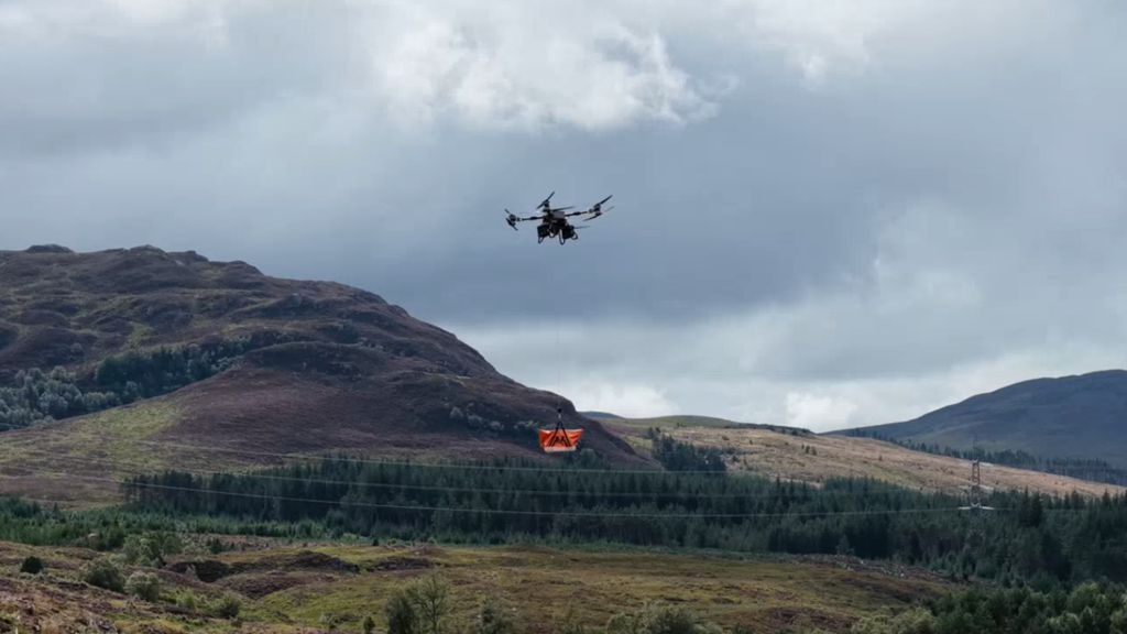 Heavy-lift drone carrying an orange bag.