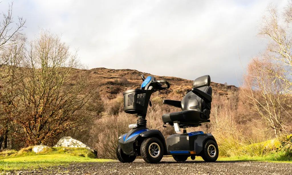 A mobility scooter sitting on a wide path with a hill behind.