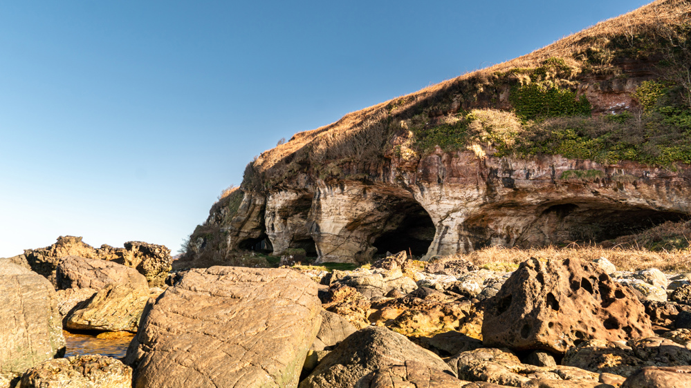 Rocks in the foreground with caves in the background.