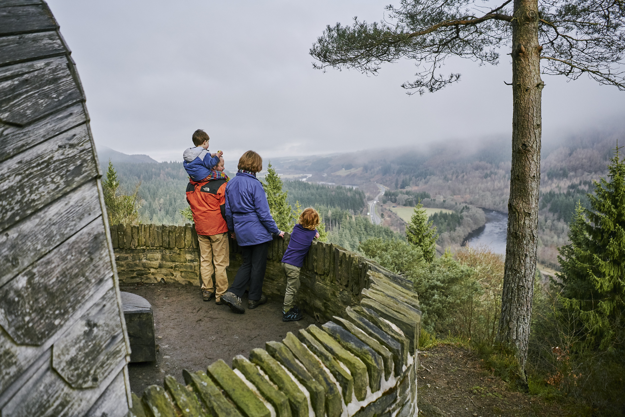 Family of two adults and two children admire view from Pine Cone Point, Craigvinean Forest, Dunkeld
