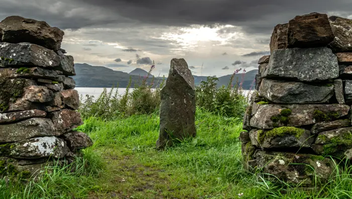 A stone wall with a single stone structure and the Isle of Mull behind it