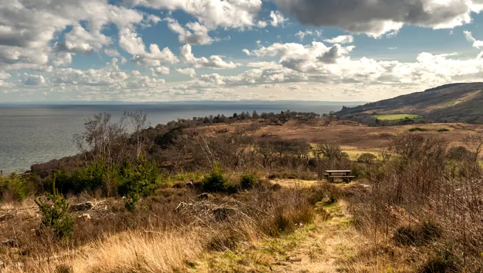 View along the coastline with sea on the left hand side and rolling hills on the right.