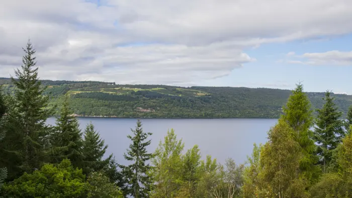 View of Loch Ness from high up with trees in the foreground.