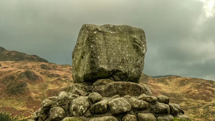 A stone monument in front of hills.