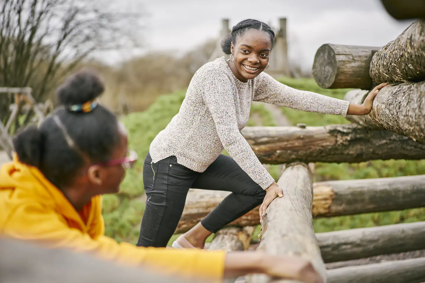 Two women lean on logs